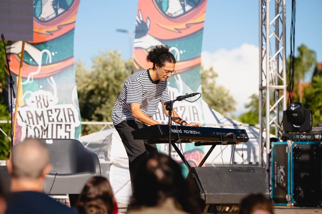 Musicista suona tastiera a festival all'aperto.