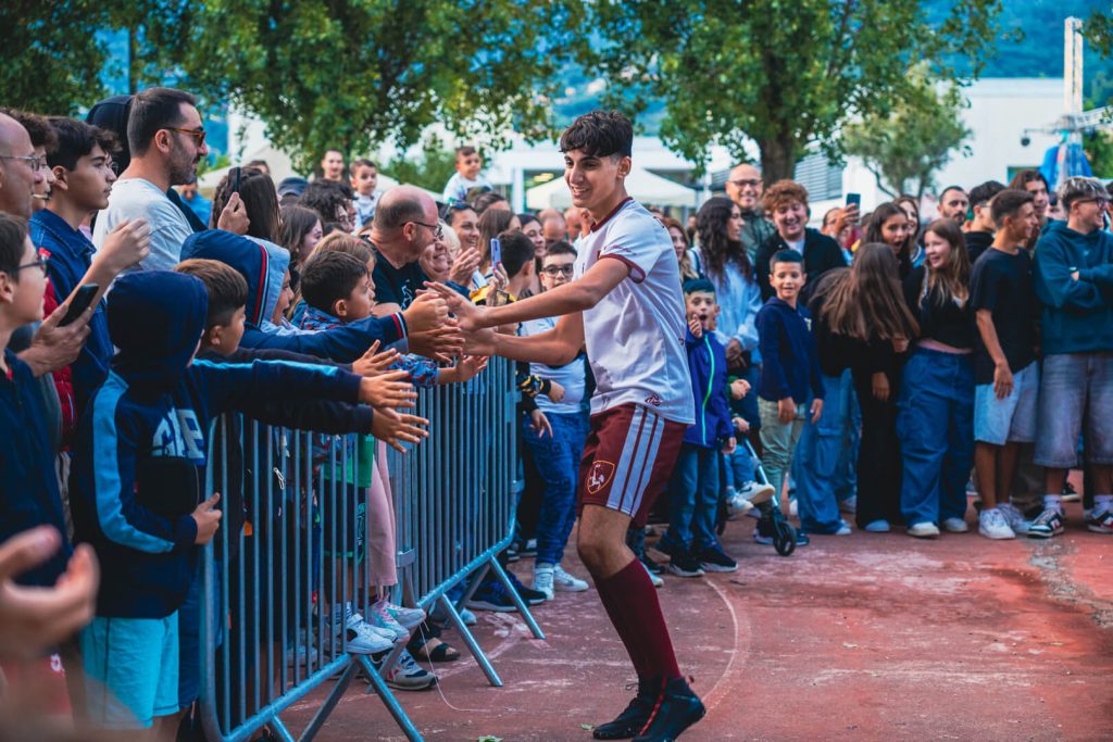 Giocatore saluta tifosi durante evento sportivo.
