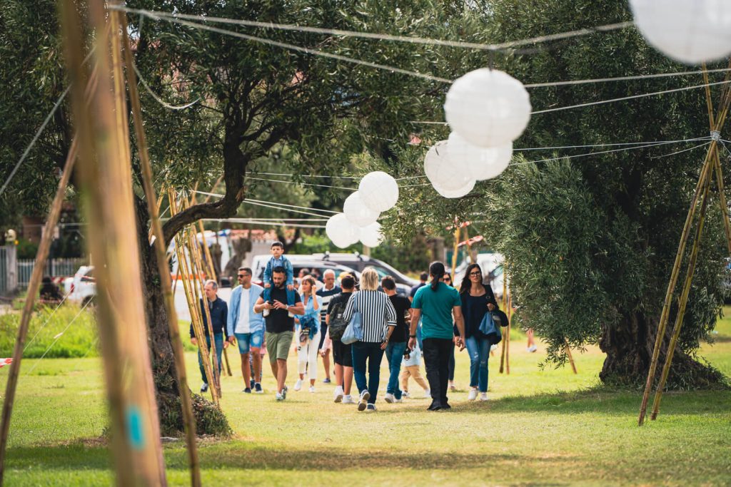 Folla cammina in un parco decorato con lanterne.