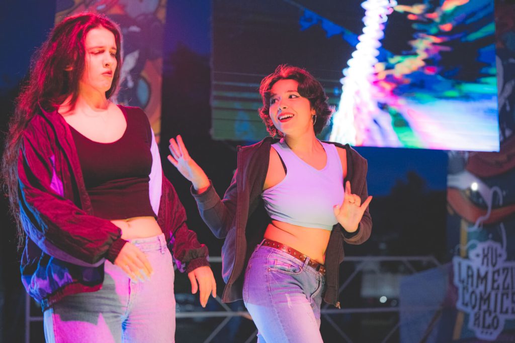 Due donne ballano su un palco colorato